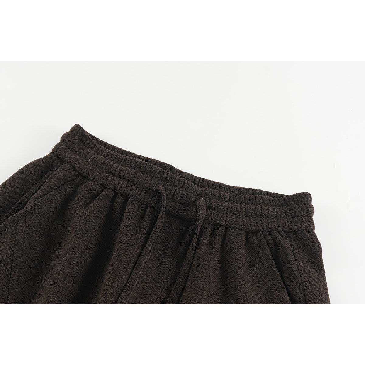 Close-up of dark brown trousers showing an elastic waistband and matching drawstring.