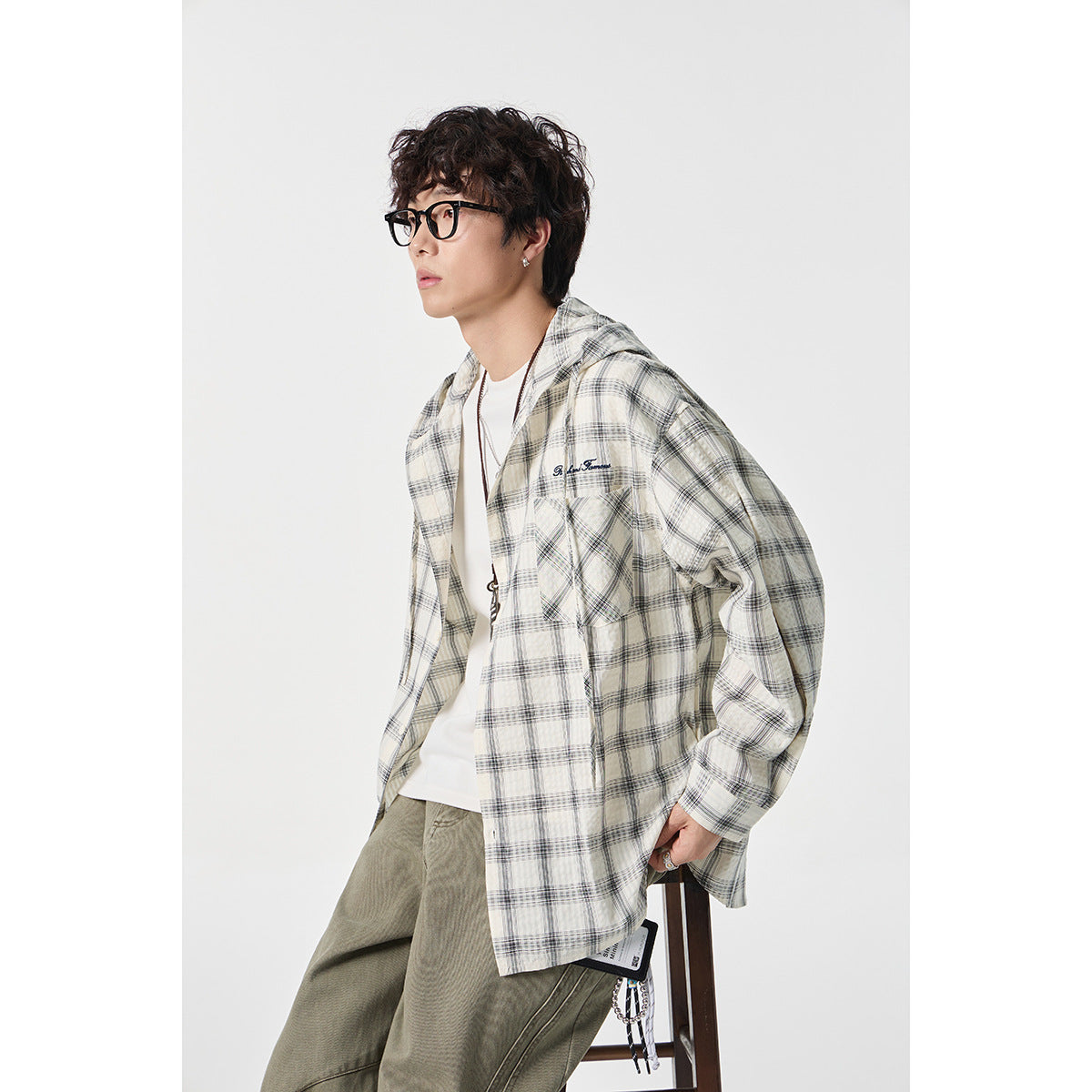 Model wearing an open cream and gray plaid hooded shirt with a chest pocket.