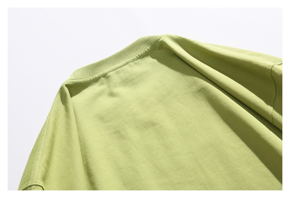 Close-up of the plain back neckline and shoulder area of a light olive-green T-shirt.
