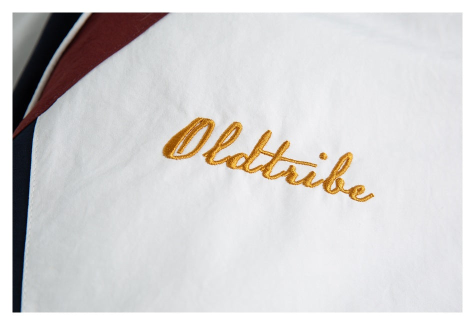 Close-up of gold script embroidery on a white jacket with burgundy and navy trim.