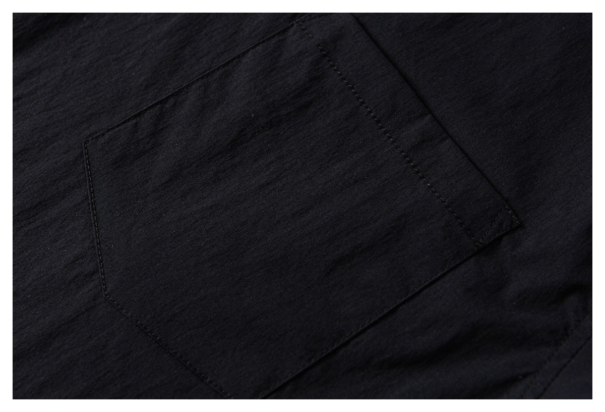 Close-up of a black garment's stitched rectangular patch pocket.