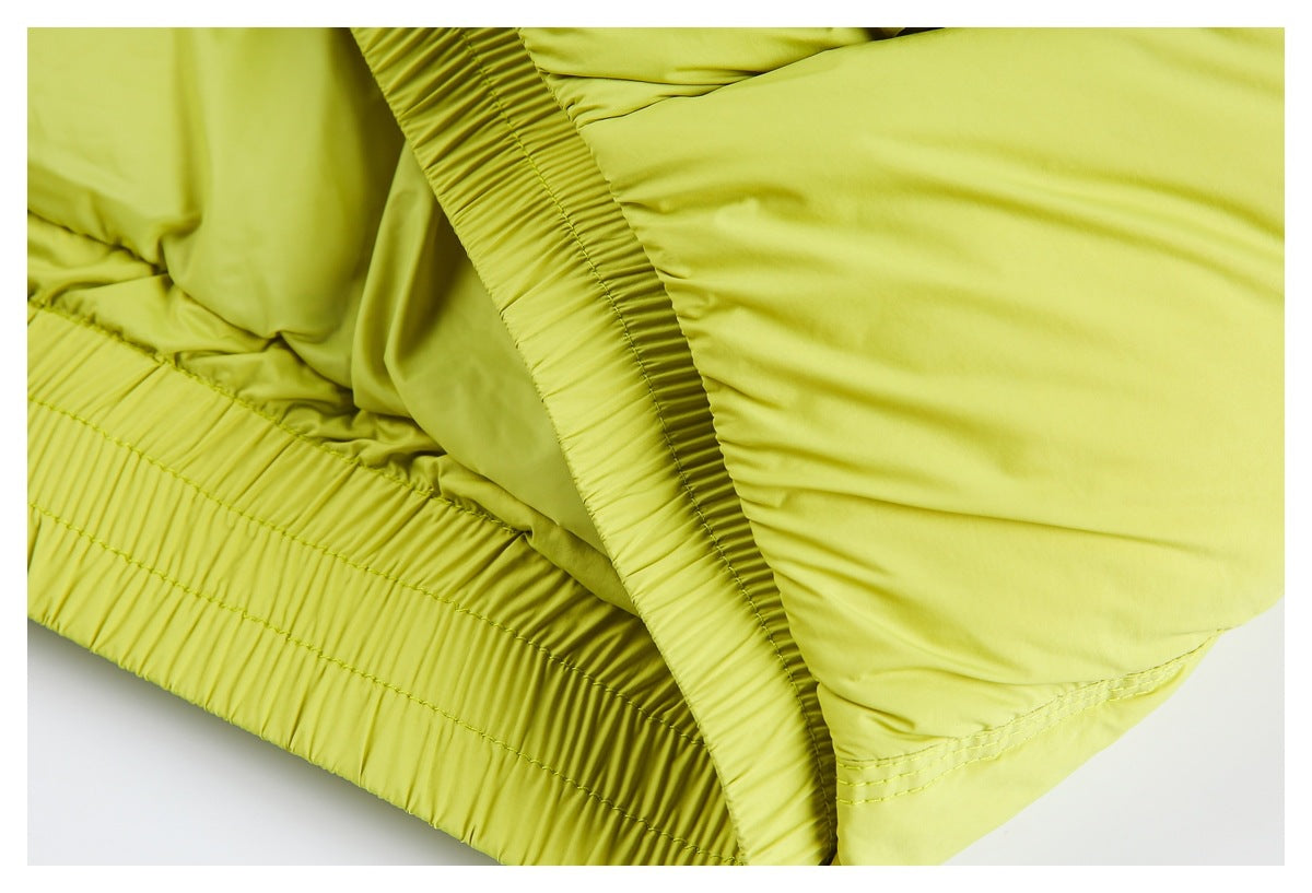 Close-up of the chartreuse jacket's gathered elastic hem and stitched side panel.