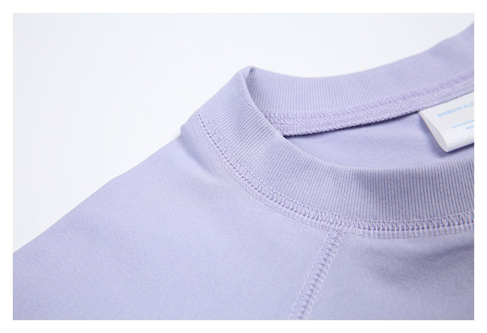 Macro view of the lavender shirt’s ribbed neckline and overlock stitching at the shoulder.
