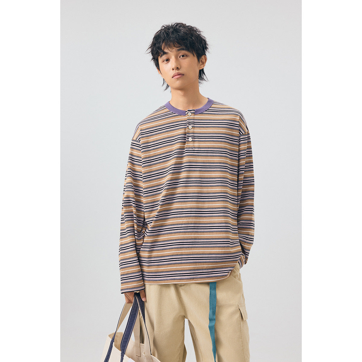 Model wearing a tan, navy and white striped long-sleeve henley with a lavender collar and beige cargo pants.