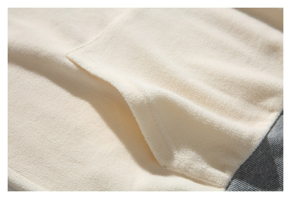 Close-up of the cream garment’s pocket seam and gray ribbed trim.