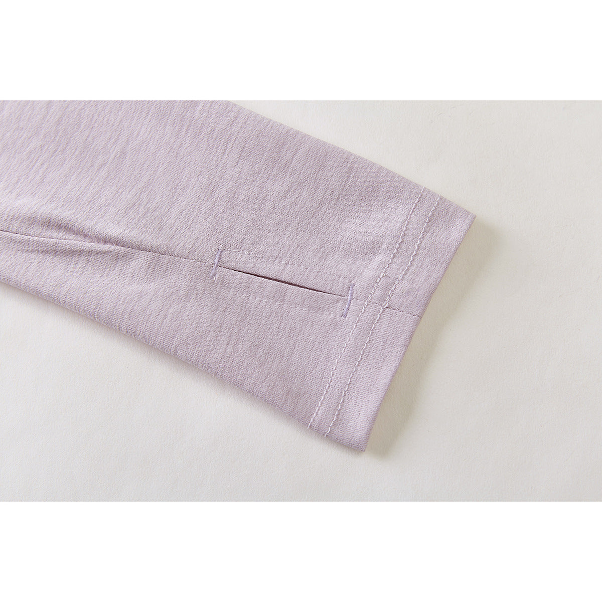 Close-up of a pale lavender sleeve cuff with a small horizontal slit and double stitching.