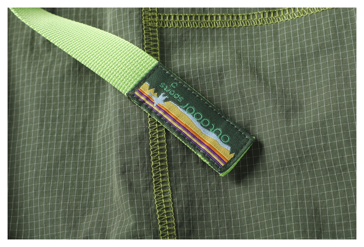 Close-up of the bright green belt tag with multicolor stripes and English lettering against the pants' check pattern.