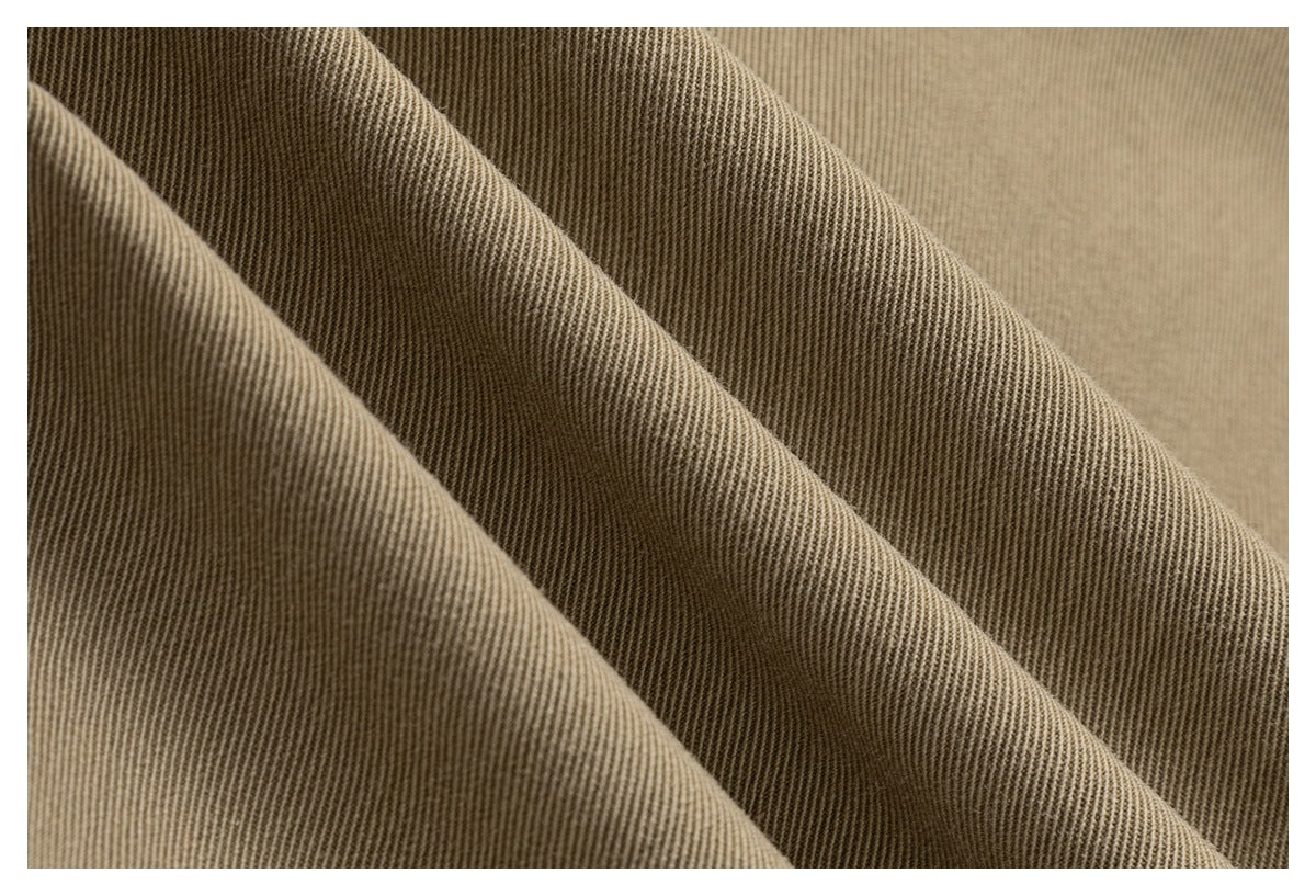 Macro view of the khaki garment’s fine diagonal fabric weave and folds.