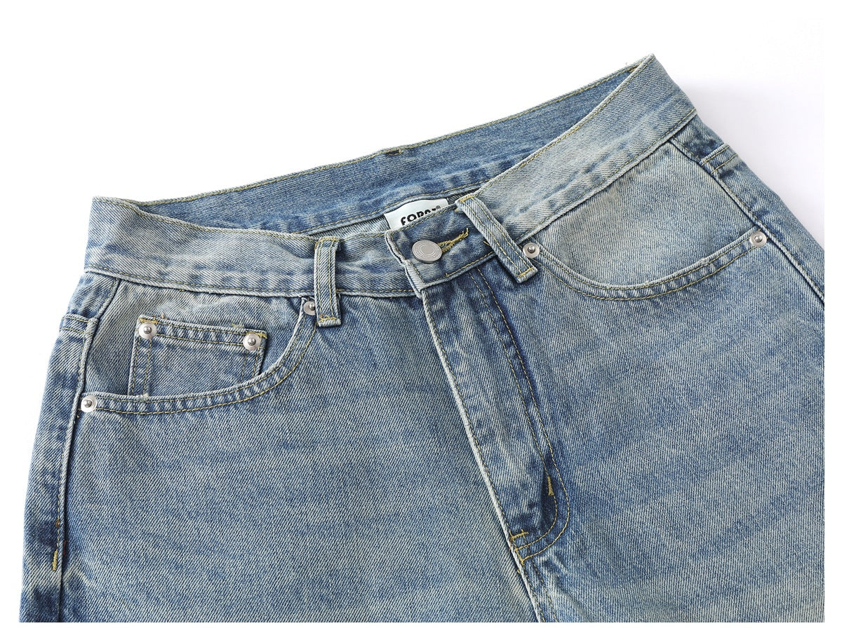 Close-up of the front waistband, button, fly, and pockets of light-wash blue jeans.