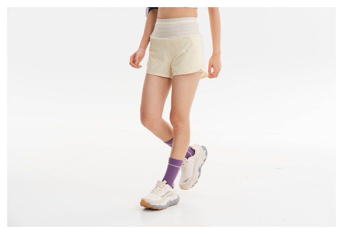Model wearing cream running shorts, shown from the front in a walking pose.