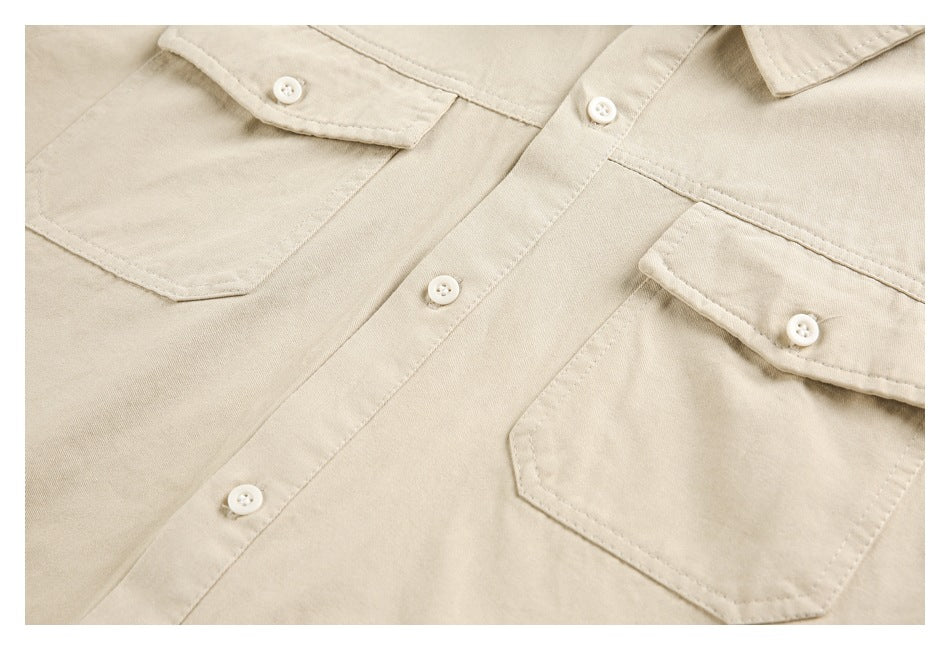 Close-up of a beige button-up shirt front with two buttoned flap chest pockets.