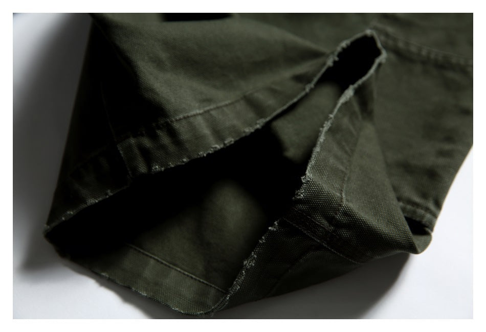 Close-up of olive trouser fabric folded open to show a stitched opening and inner seam.