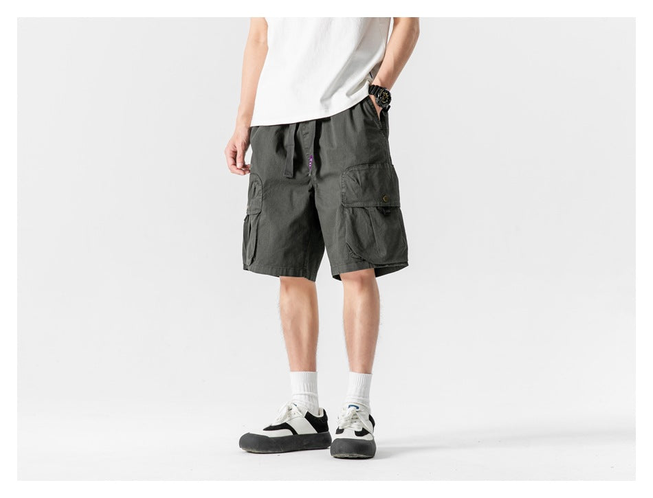 Front view of a model wearing dark charcoal cargo shorts with a drawstring waist and large flap pockets.