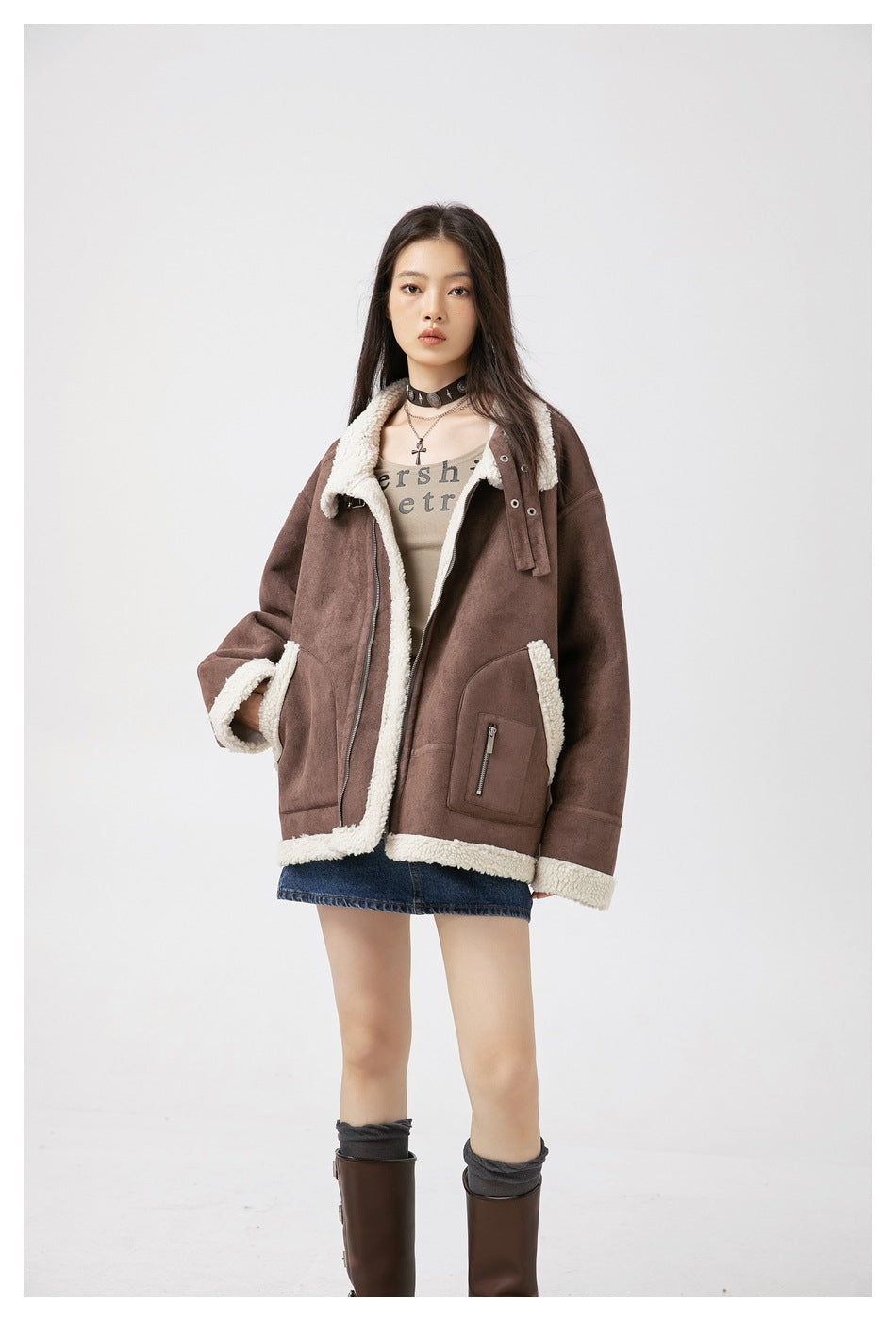 Model wearing an open brown jacket with cream fleece trim over a beige top and denim skirt.