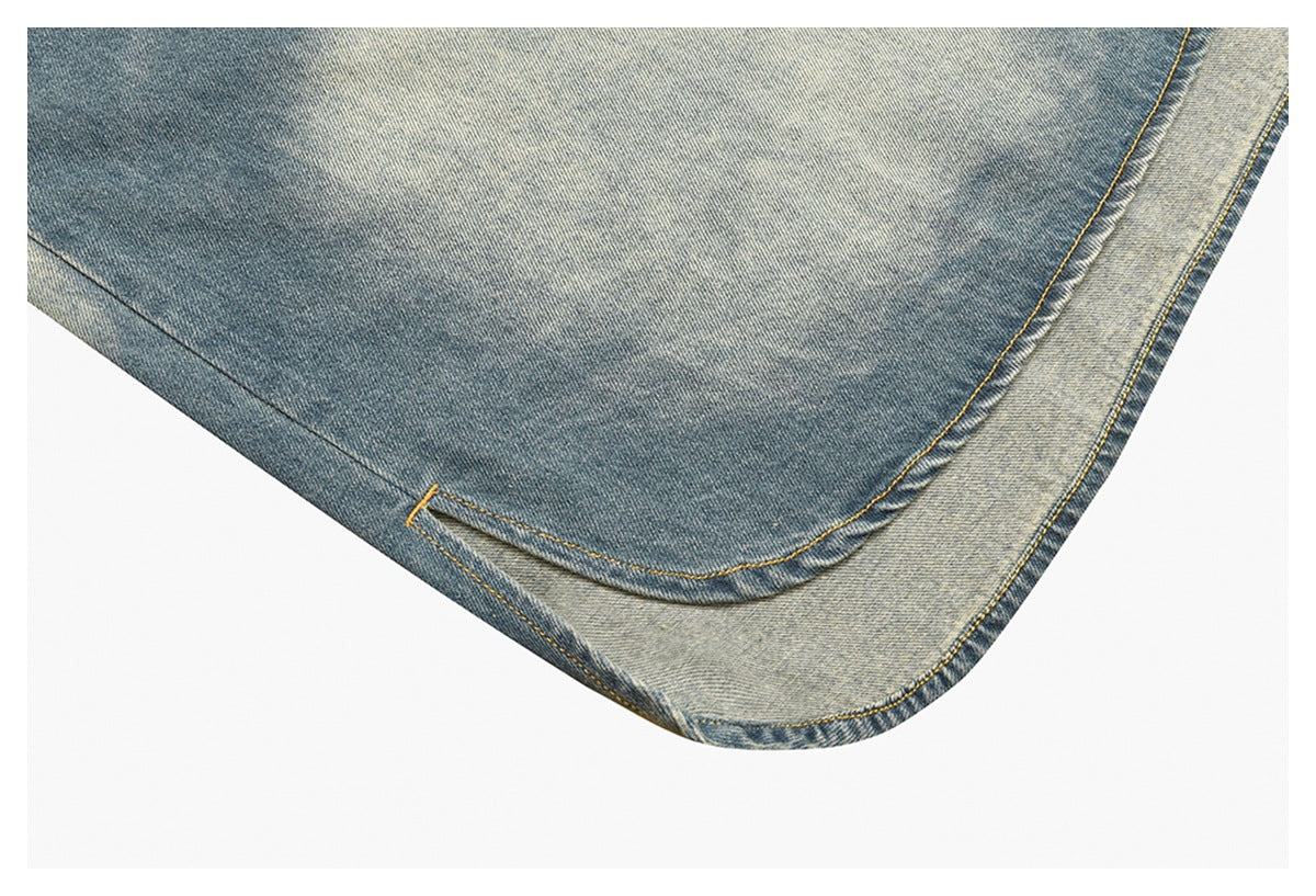 Close-up of the denim jacket’s curved hem and layered edge, with contrasting washes and yellow stitching.