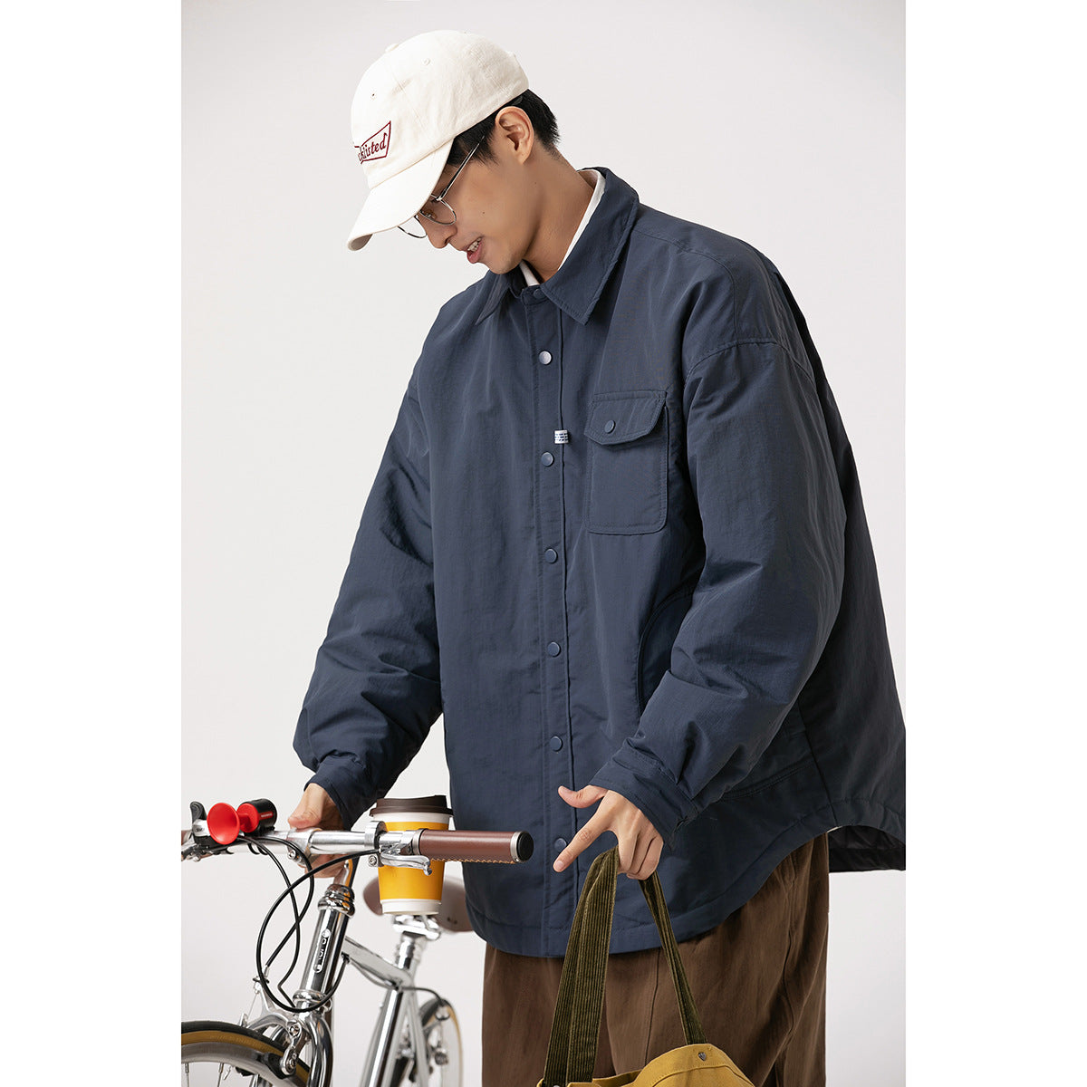 Closer angled view of a model wearing a navy jacket with a pointed collar, snap closures, and a flap chest pocket.