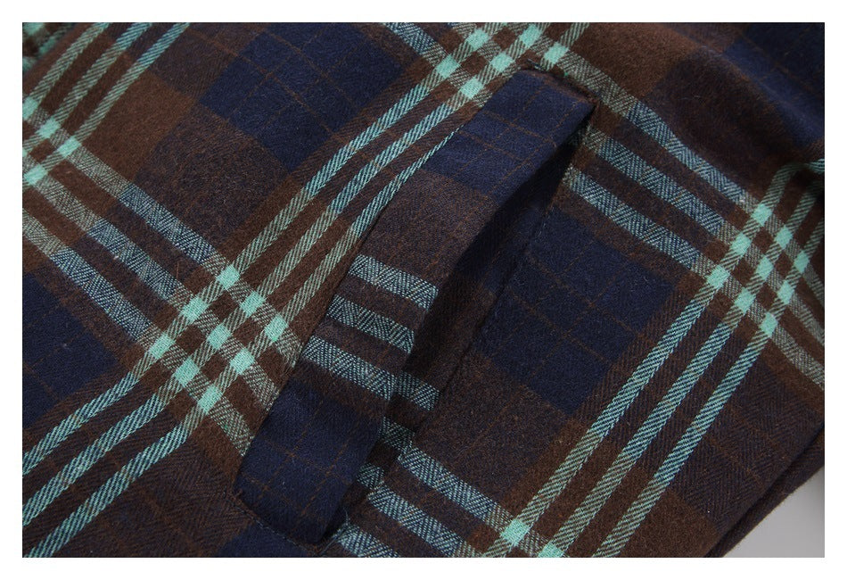 Close-up of a flap pocket on a brown, navy, and aqua plaid jacket.