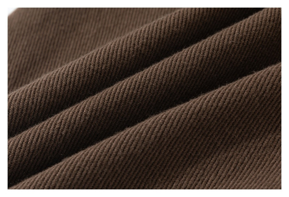 Macro view of the diagonal ribbed texture of brown trouser fabric.