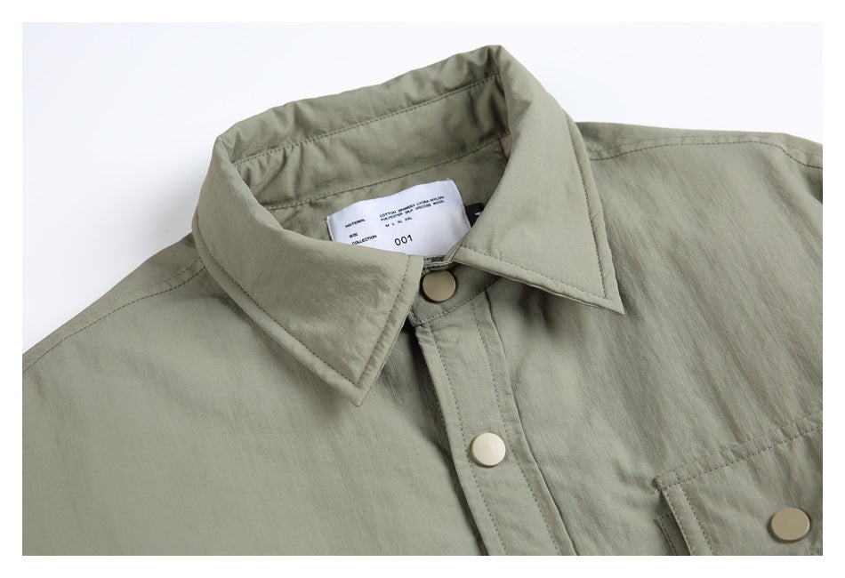 Close-up of the gray-green jacket's pointed collar, snap-button placket and small inside neck label.