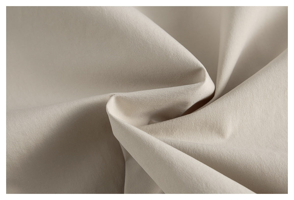 Close-up of light beige fabric draped into soft folds, showing its fine surface texture.