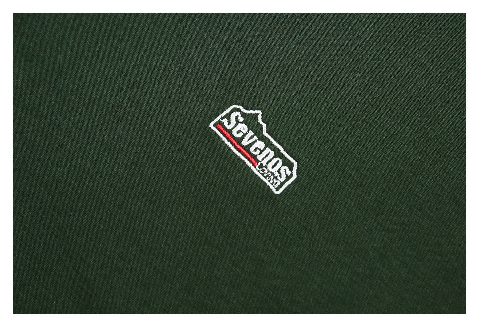 Small embroidered white-outlined logo with red accent on dark green fabric.