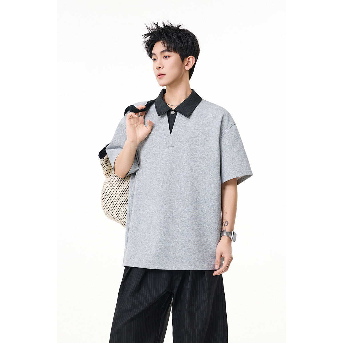 Closer view of a model wearing an oversized light gray polo-style shirt with a contrasting dark collar.