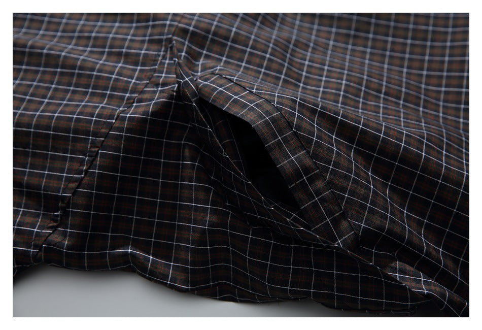 Close-up of a slanted pocket opening on dark plaid fabric with fine white and red lines.