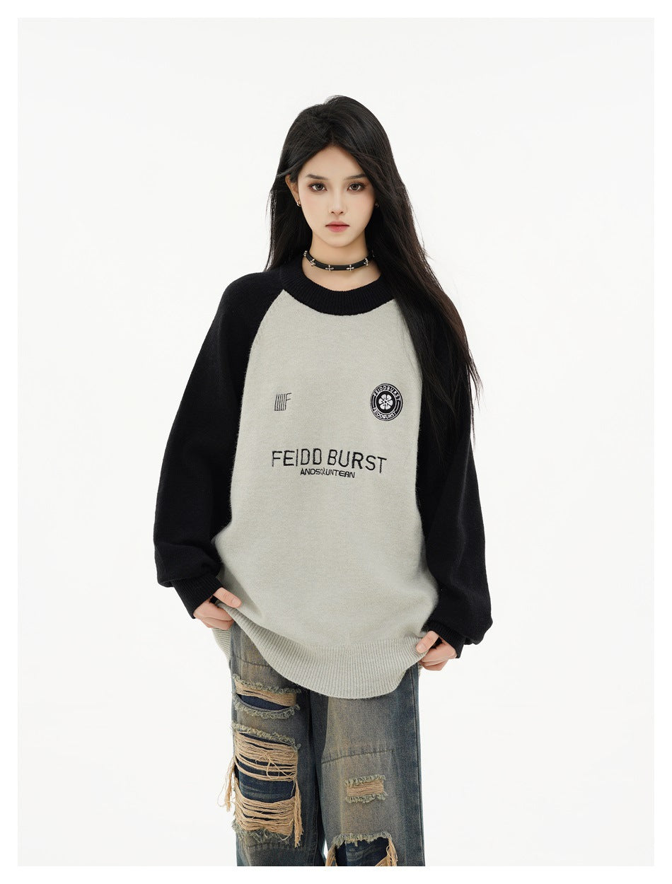 Model wearing a gray and black raglan crewneck sweater with ripped jeans, front view with embroidered chest details
