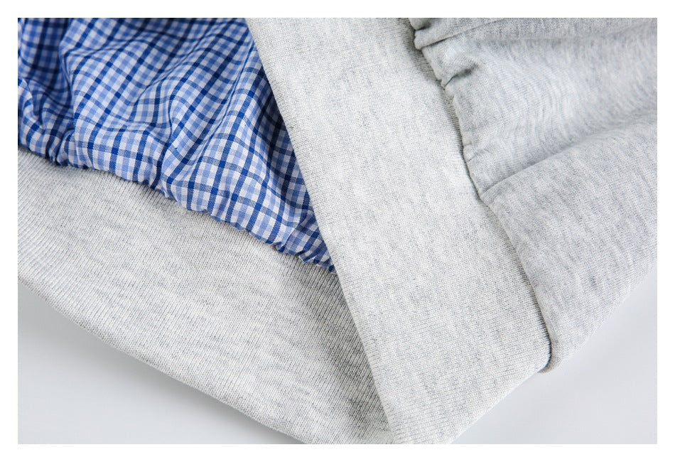 Close-up of blue-and-white gingham lining beside light gray knit fabric and a ribbed edge.