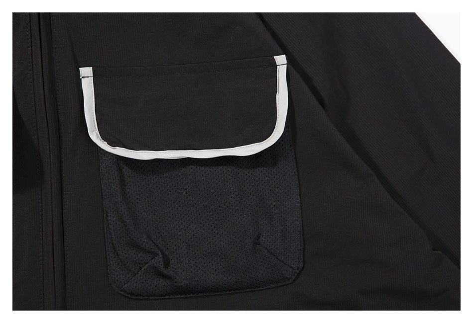 Close-up of a black garment pocket with a mesh lower panel and white piping around the flap.