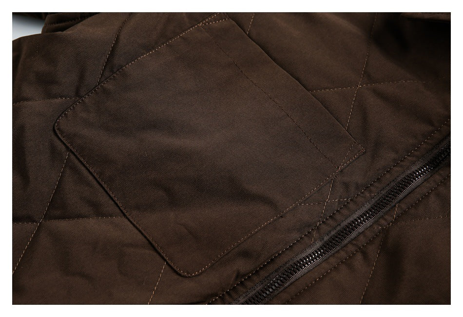 Close-up of a dark brown quilted jacket showing a flap pocket, stitched panels, and a diagonal zipper.