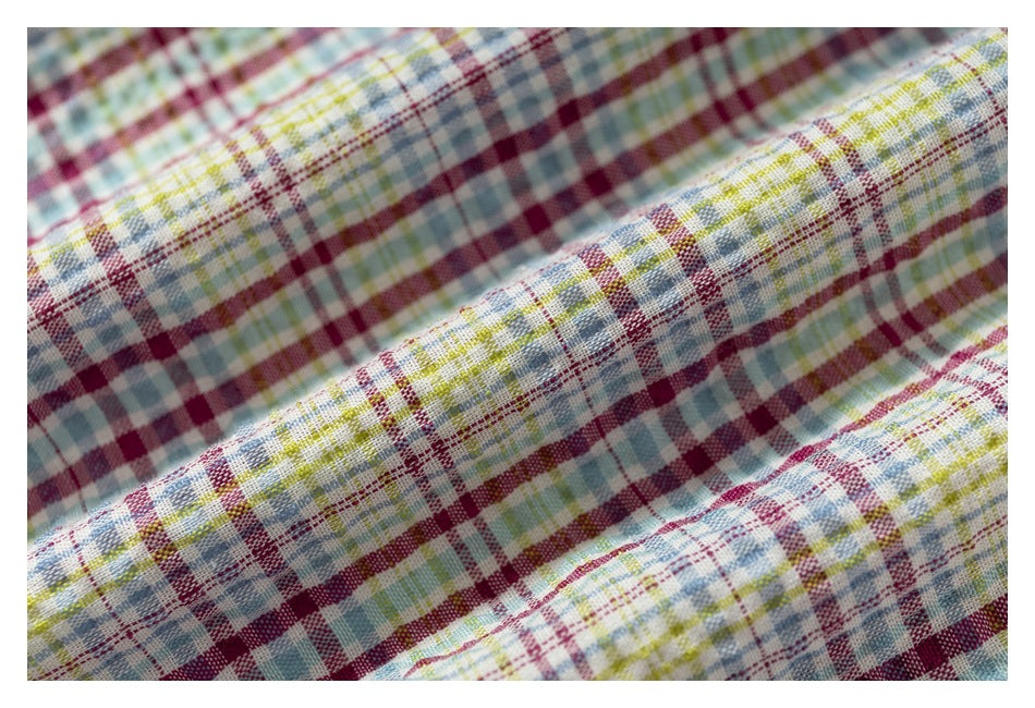 Macro view of the woven burgundy, blue, green, and yellow plaid fabric on a shirt.