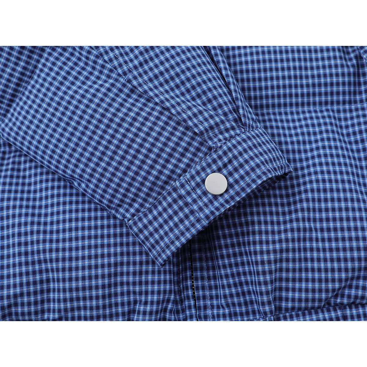 Close-up of a blue checked jacket sleeve cuff with a silver snap.