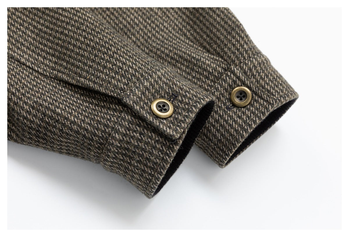 Close-up of a brown and charcoal herringbone jacket cuff with two antique-gold buttons.