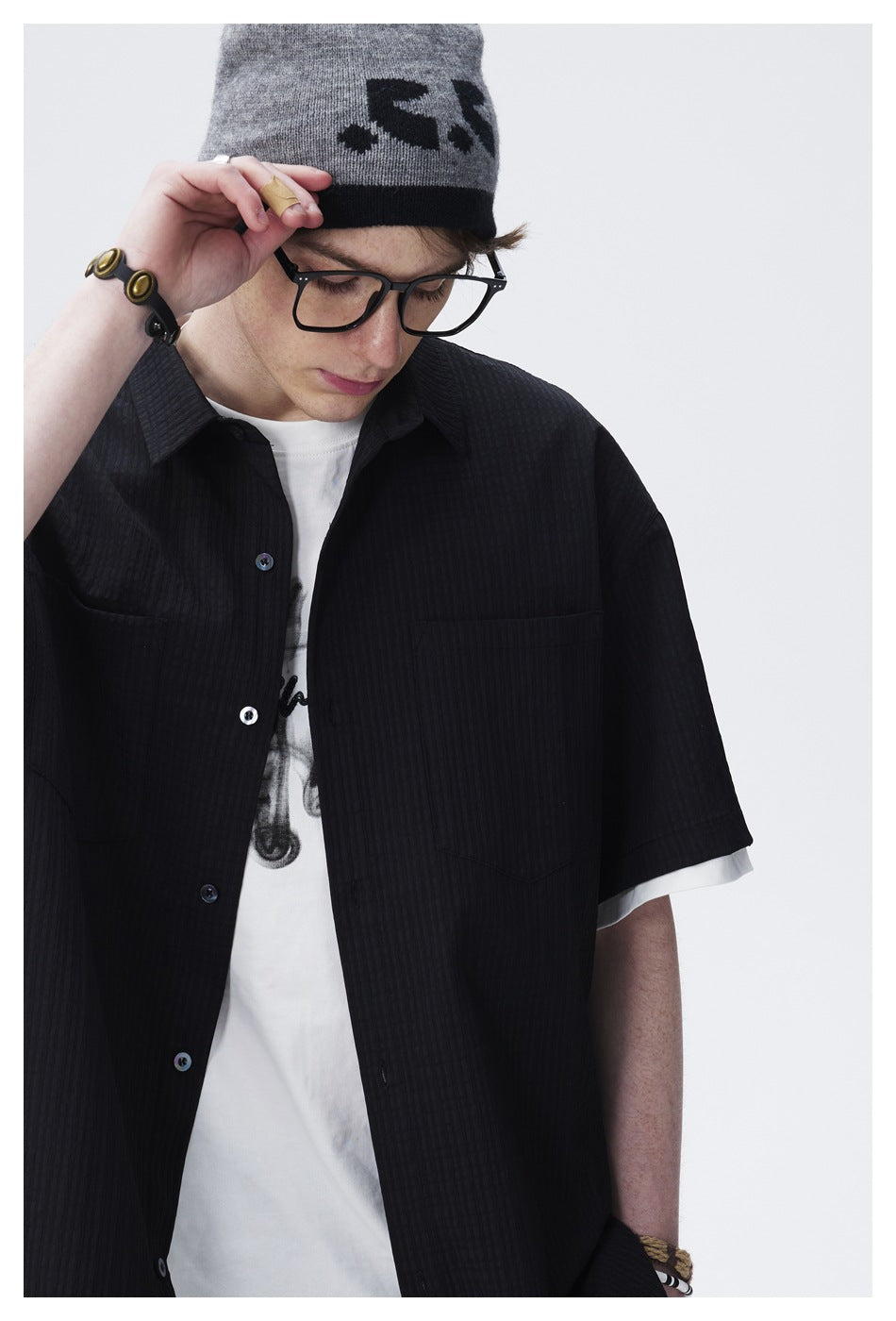 Close view of a model wearing a black short-sleeve button-up shirt with two chest pockets.