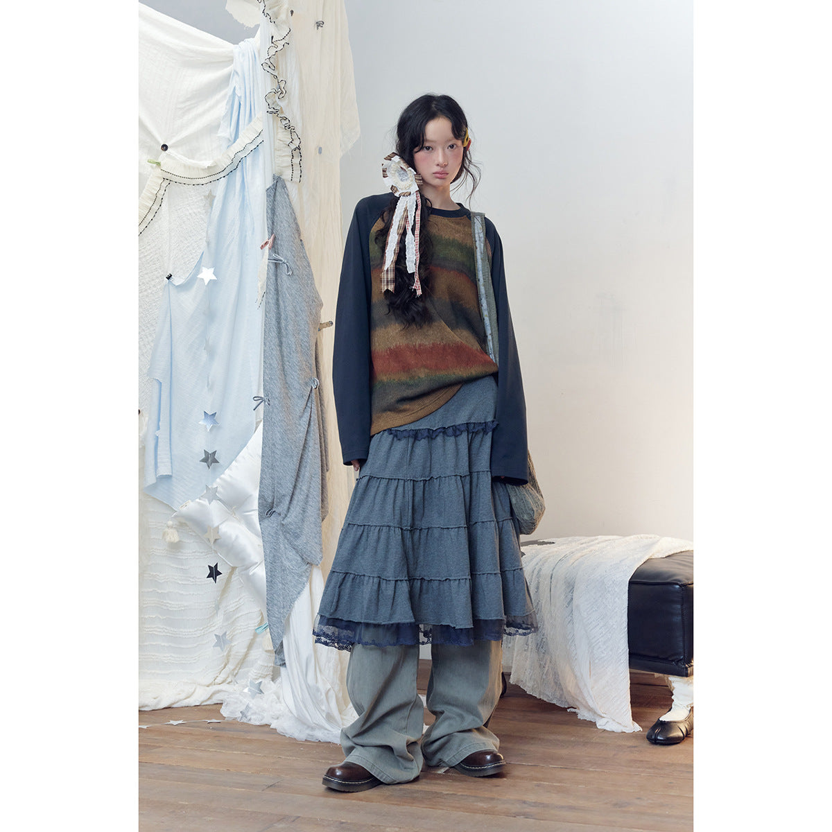 Full-length view of a model in a brown multicolor striped top with navy sleeves, gray tiered skirt and loose pants.