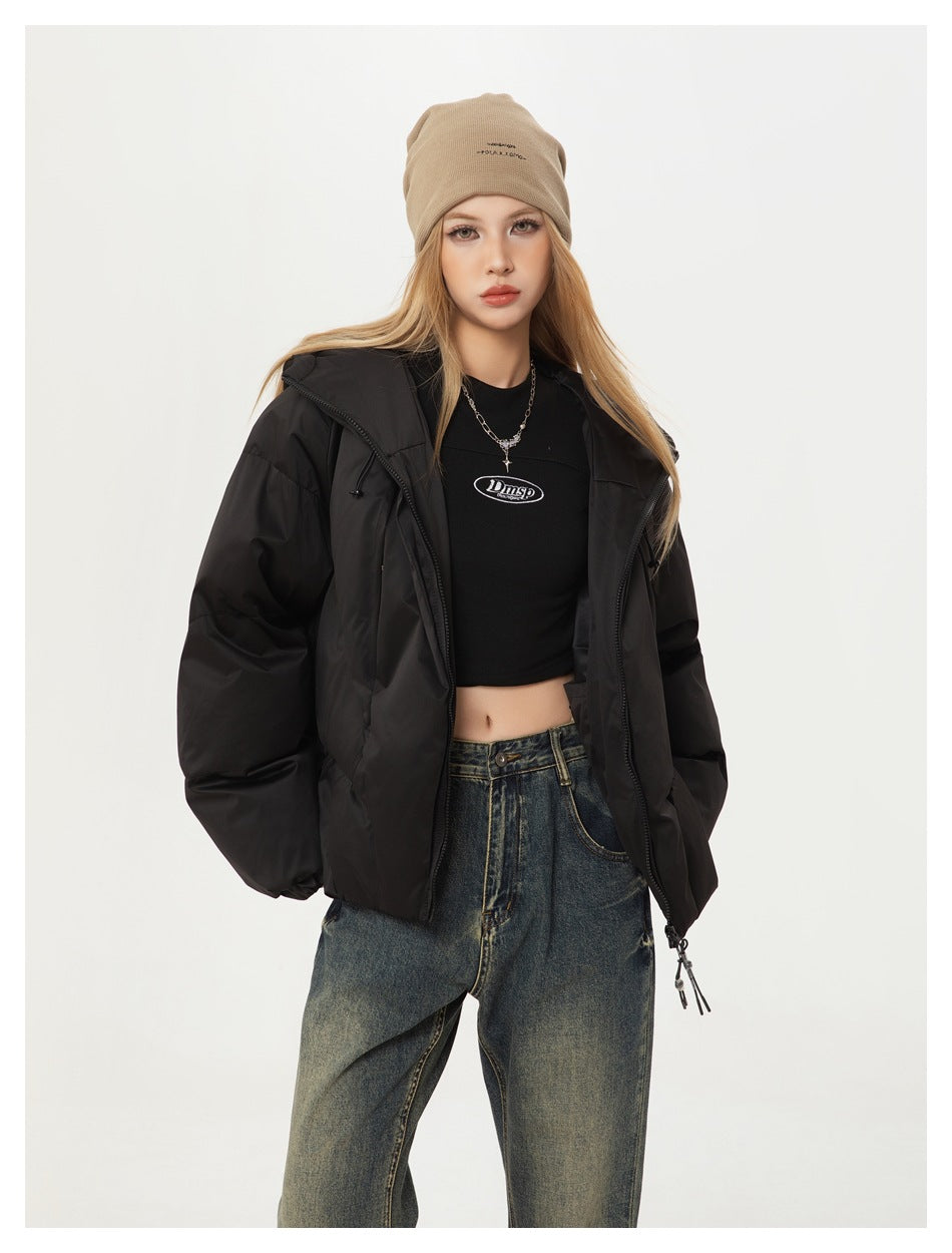 Model wearing an open black hooded puffer jacket over a black crop top with loose dark jeans.