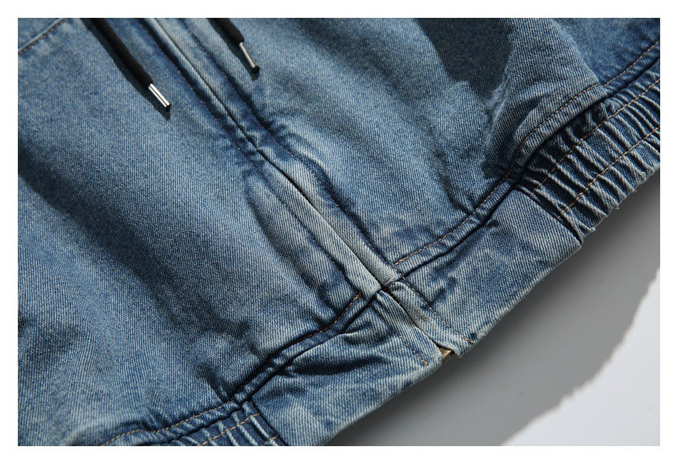 Close-up of the denim hoodie's front seam, drawstring ends, and gathered hem.