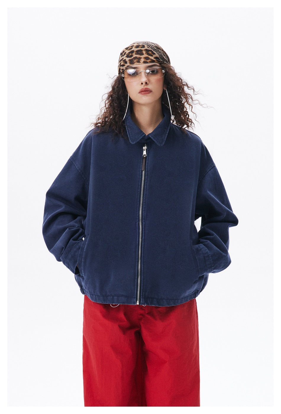 Front view of a person wearing an oversized navy zip-up jacket with a pointed collar and roomy sleeves.