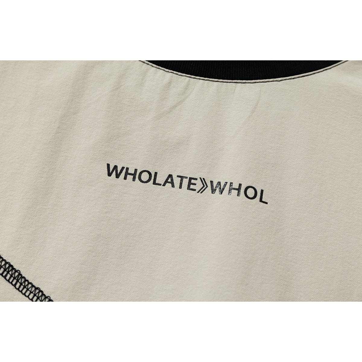 Close-up of black lettering printed on cream fabric below a black neckline.