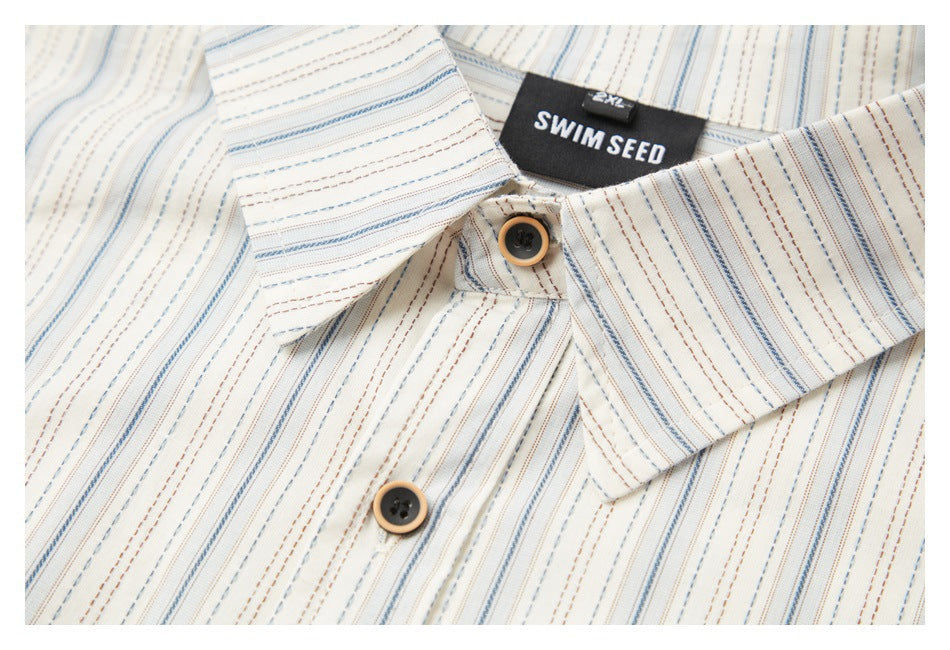 Close-up of the ivory striped shirt collar, two buttons, and black neck label.