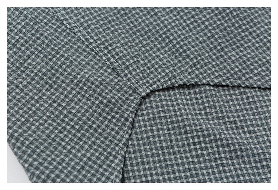 Close-up of gray check shirt seams where two fabric panels meet.