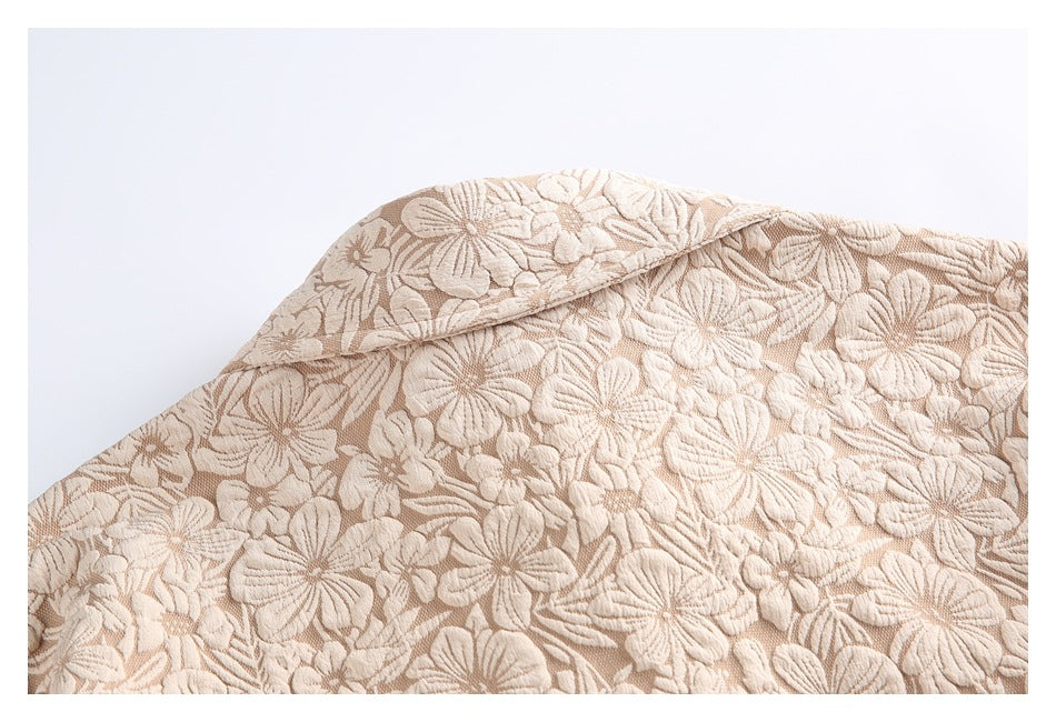 Close-up of the beige garment's collar and dense raised floral pattern.