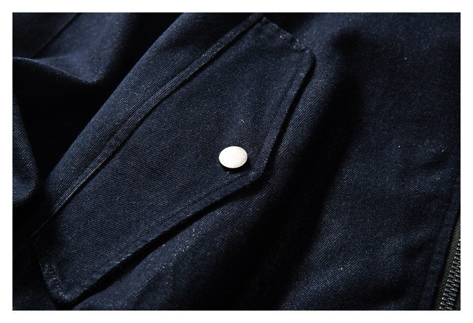 Close-up of a dark indigo jacket's snap-fastened flap pocket and zipper edge.