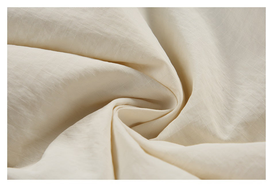 Close-up of softly draped cream fabric showing its subtle woven texture.
