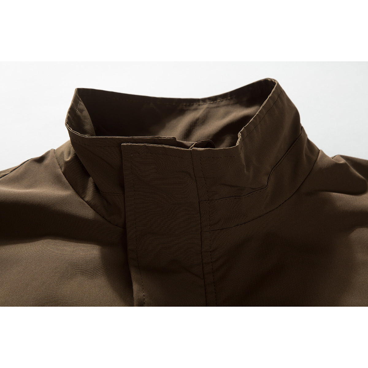 Close-up of a dark brown jacket's raised collar and front storm flap.