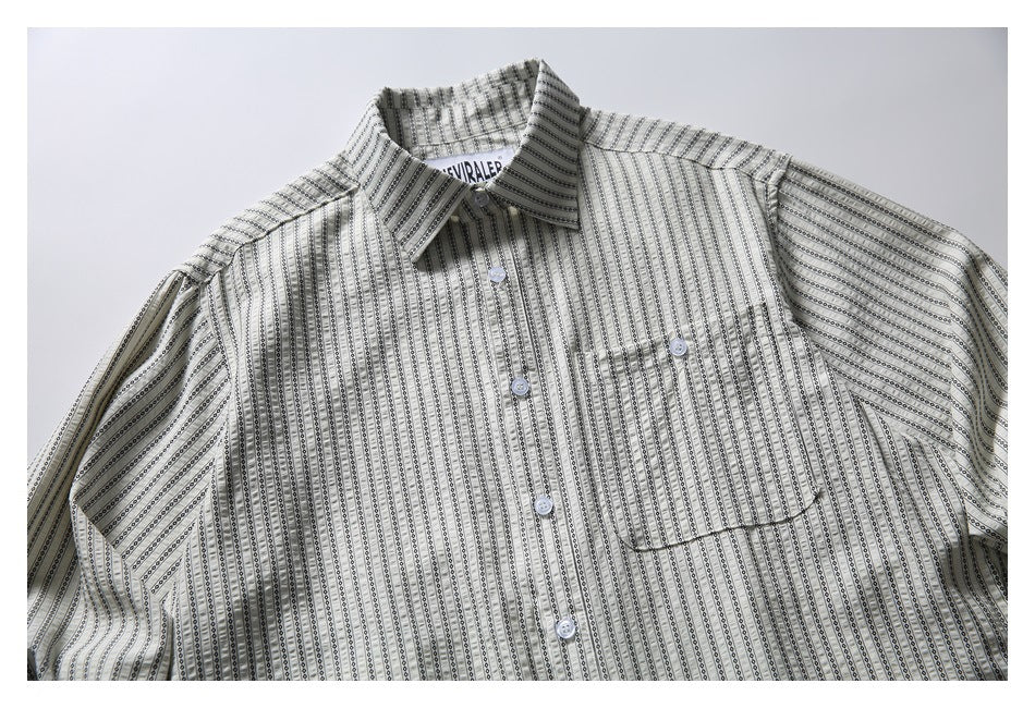Close front view of a light button-front shirt with narrow black geometric stripes, a pointed collar, and chest pocket.