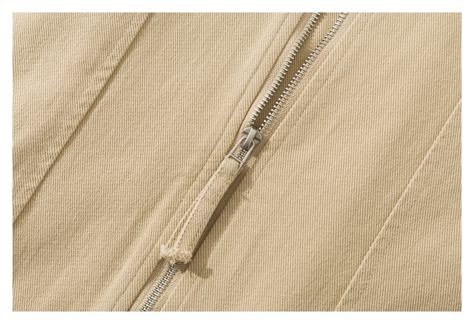 Close-up of a metal zipper on beige garment fabric.
