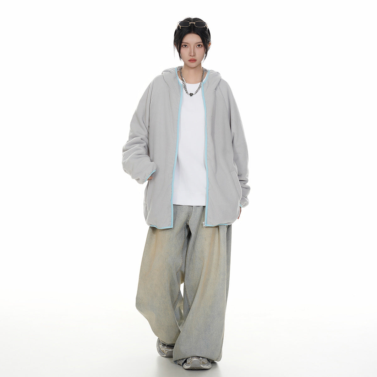 Model wearing an open light gray hooded zip jacket with pale blue trim, a white top, and loose light-wash jeans.
