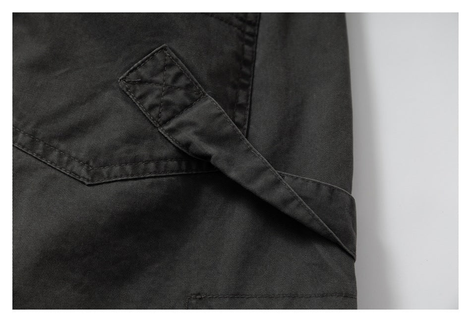 Close-up of a dark charcoal garment with a stitched fabric tab crossing a seam.